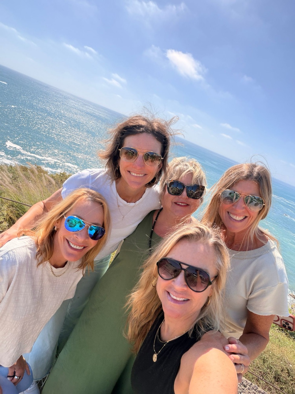 Five friends taking a selfie on a cliff above the ocean